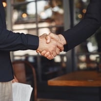 Zwei Personen geben sich die Hand in einem Café.