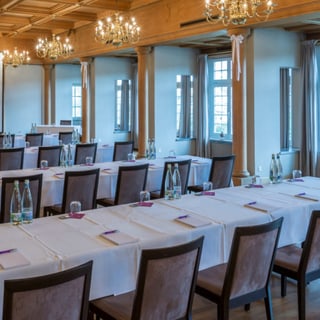 Konferenzraum mit Tischen, Stühlen und Leinwand.",