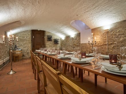 Langer Tisch in einem Gewölbekeller mit Kerzenleuchtern.