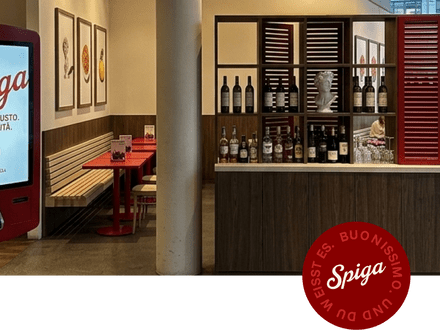 Innenbereich eines Restaurants mit rotem Automaten und Regal mit Flaschen.