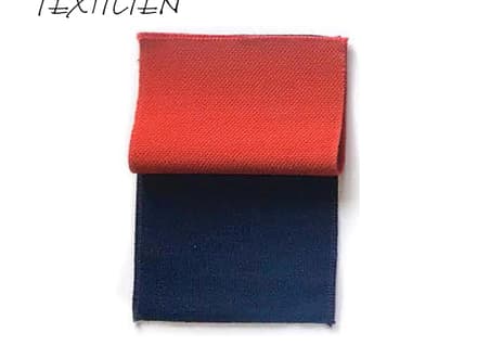 Rote und blaue Stoffprobe mit Textilien-Schriftzug.