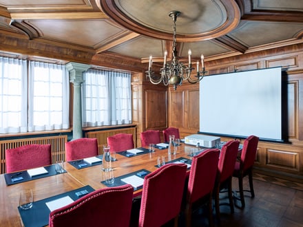 Konferenzraum mit Holzwänden und rotem Samtstühlen.