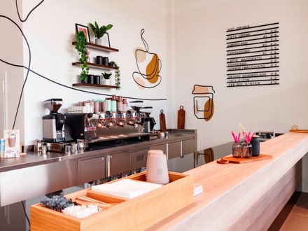 Modernes Café mit langen Holztheke und Wanddekorationen.