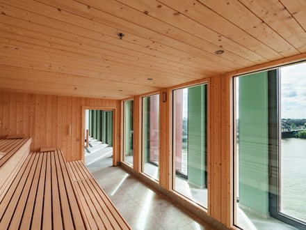 Holzsauna mit grossen Fenstern und Blick auf das Wasser.
