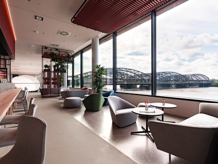 Moderner Raum mit Sesseln und grossen Fenstern mit Blick auf die Brücke.