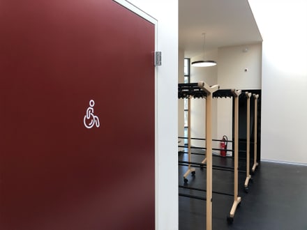 Rote Tür mit Rollstuhlsymbol, daneben Garderobe.