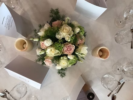 Blumenstrauss auf gedecktem Tisch mit Menükarten und Gläsern.