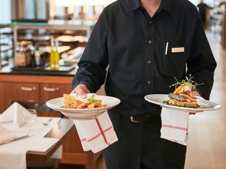 Kellner serviert zwei Teller mit Gourmetgerichten im Restaurant.