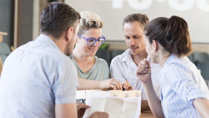 Vier Personen diskutieren an einem Tisch.
