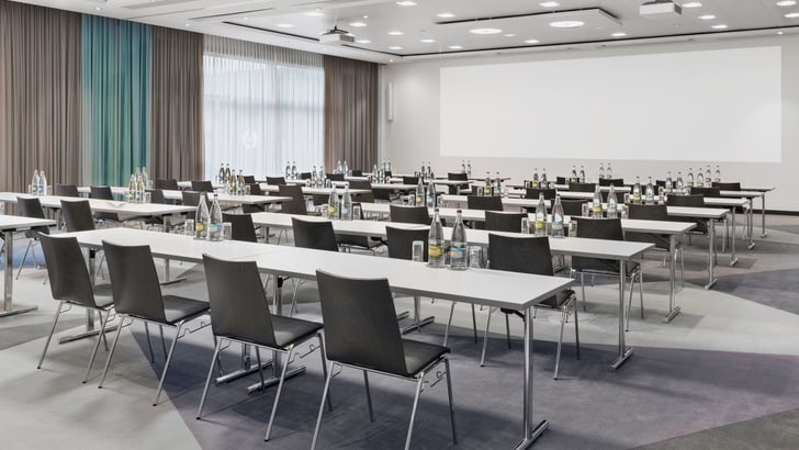 Leerstehender Konferenzraum mit Tischen und Stühlen.
