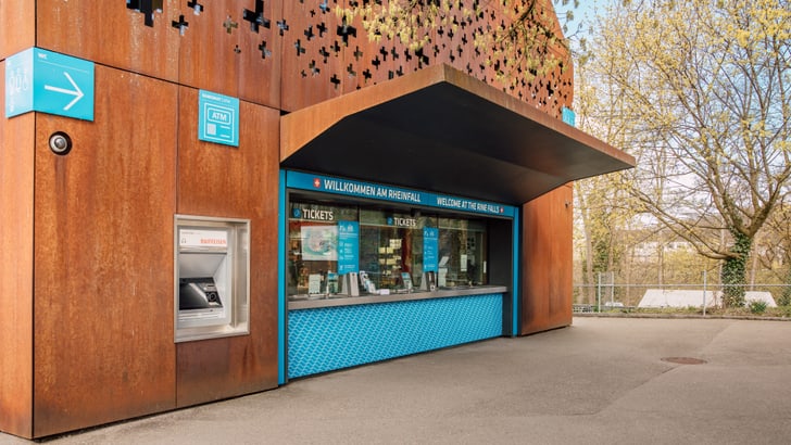Eingang mit Ticketschalter und Bankautomat im Freien.