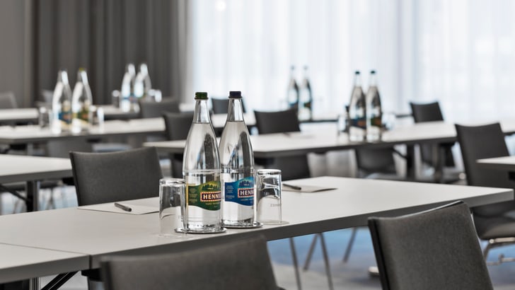 Leerer Konferenzraum mit Wasserflaschen auf Tischen.