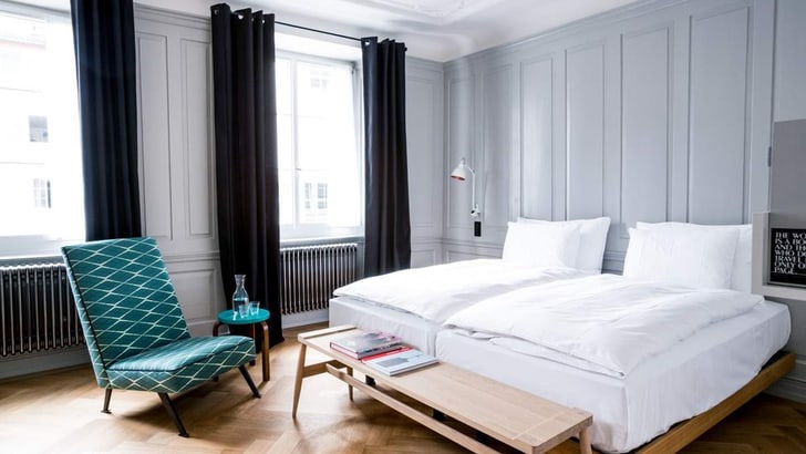 Modernes Schlafzimmer mit Doppelbett und Sessel am Fenster.