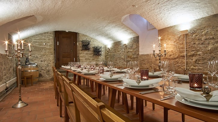 Langer Tisch in einem Gewölbekeller mit Kerzenleuchtern.