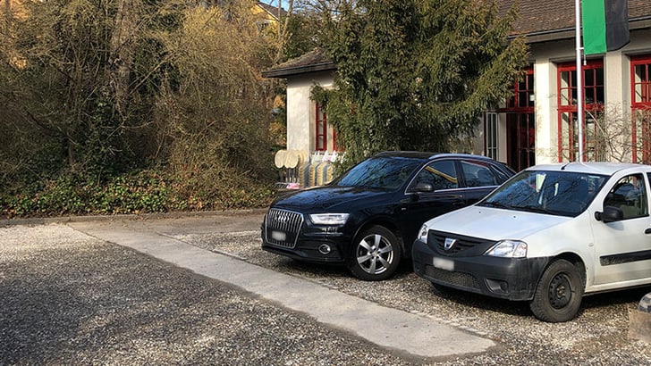 Zwei geparkte Autos vor Gebäude im Freien.