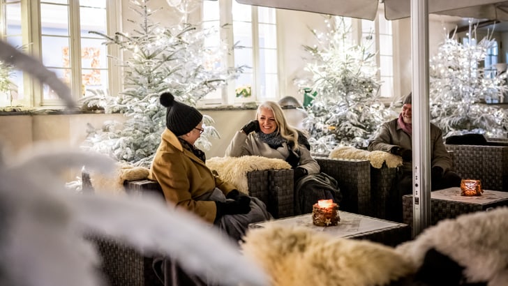 Menschen sitzen bei einer winterlichen Kulisse in einem gemütlichen Innenhofbereich.