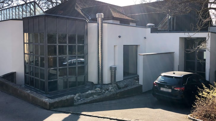 Modernes Gebäude mit Glasfassade und geparktem Auto bei Tageslicht.