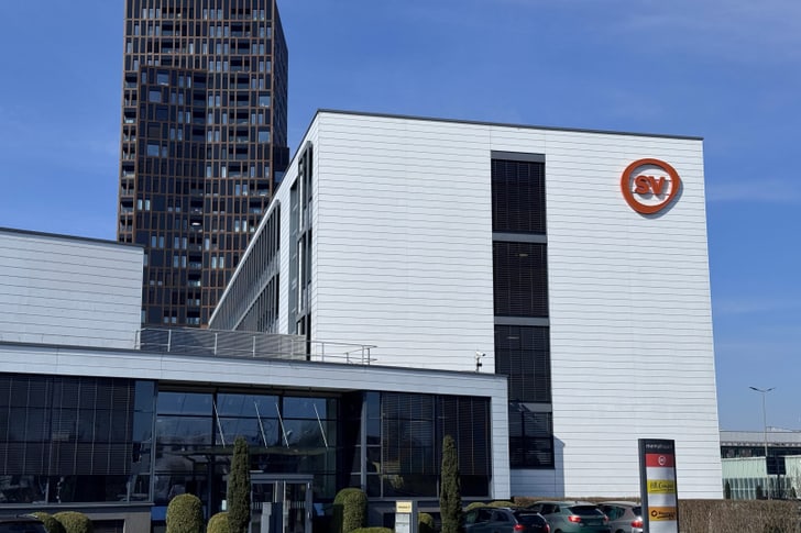 Modernes Gebäude mit Firmenlogo bei sonnigem Himmel.