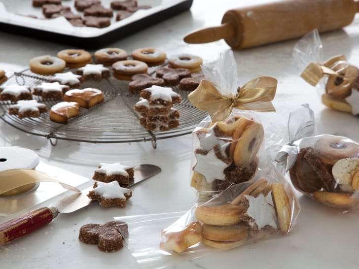 Weihnachtsplätzchen, Geschenkverpackungen und Backutensilien auf Tisch.