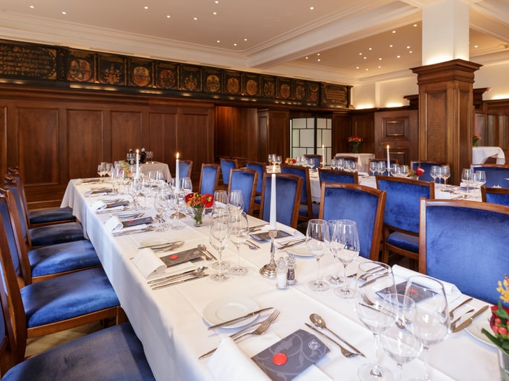 Elegantes Restaurant mit langen, eingedeckten Tischen und blauen Stühlen.