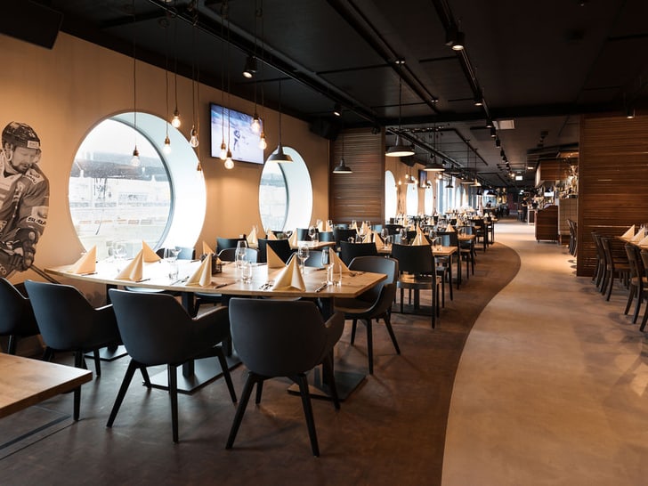 Restaurant mit gedeckten Tischen, Fenster mit Sportdekorationen.
