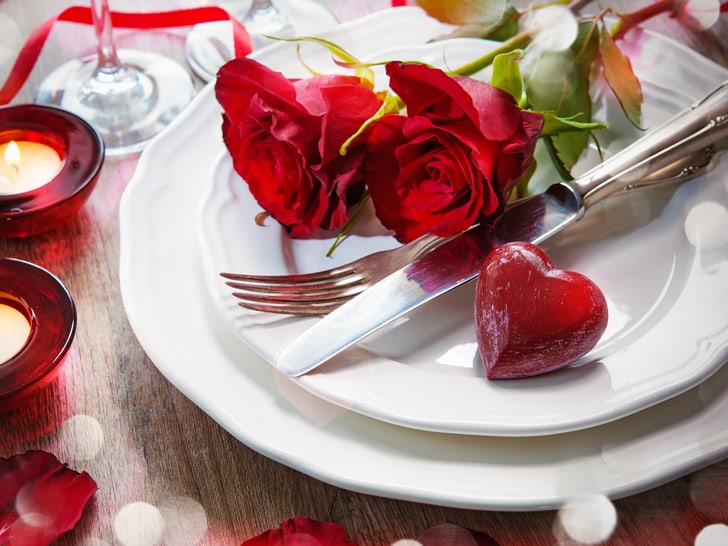 Romantisches Abendessen-Setup mit Rosen und Kerzen.
