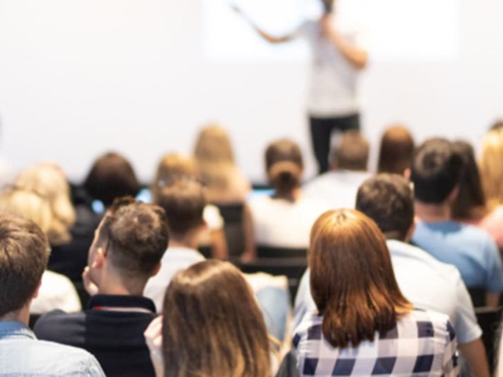 Person hält Präsentation vor Publikum in einem Raum.
