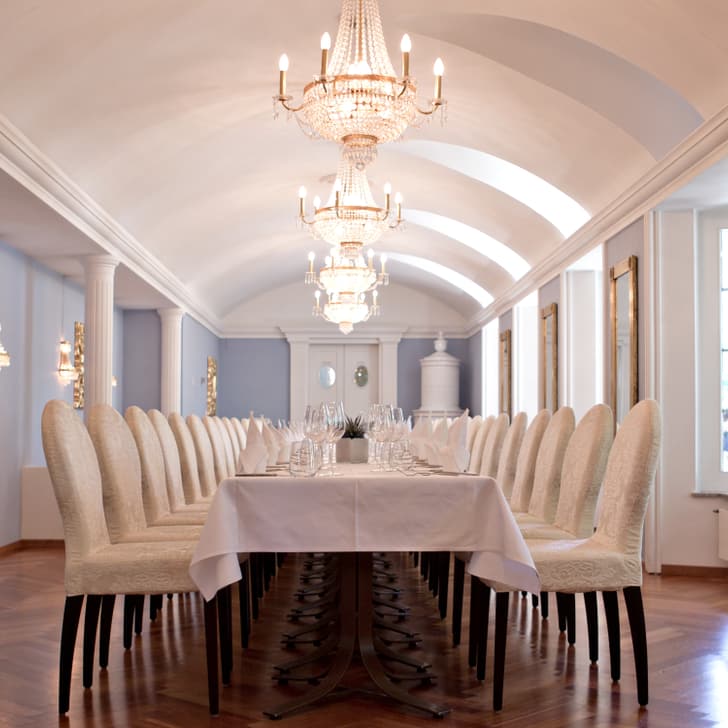 Eleganter Speisesaal mit langen Tischen und Kronleuchtern.