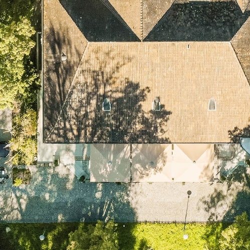 Luftaufnahme eines Gebäudes im Grünen mit Parkplatz.