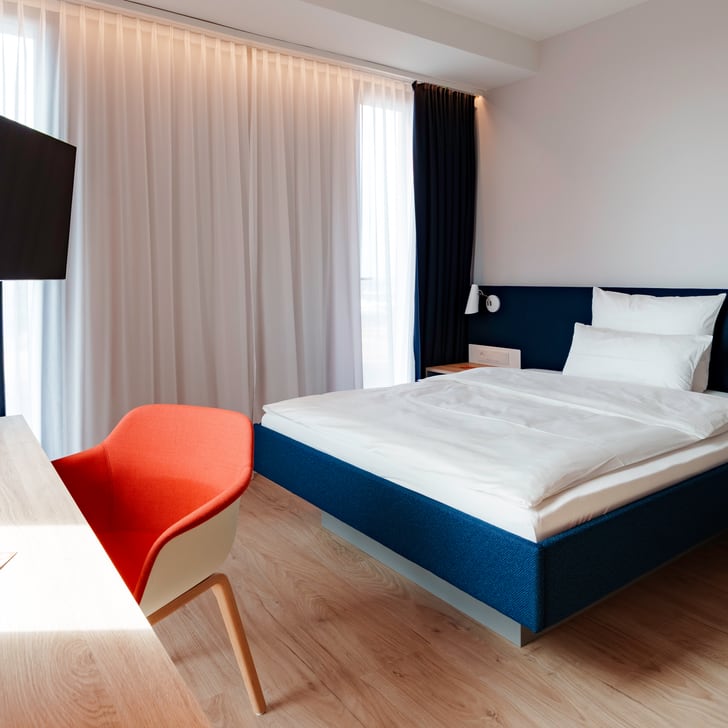 Modernes Schlafzimmer mit Bett, Schreibtisch und Fernseher.