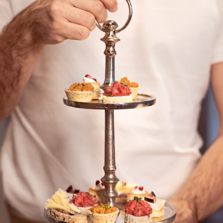 Person hält Etagere mit Vorspeisen.