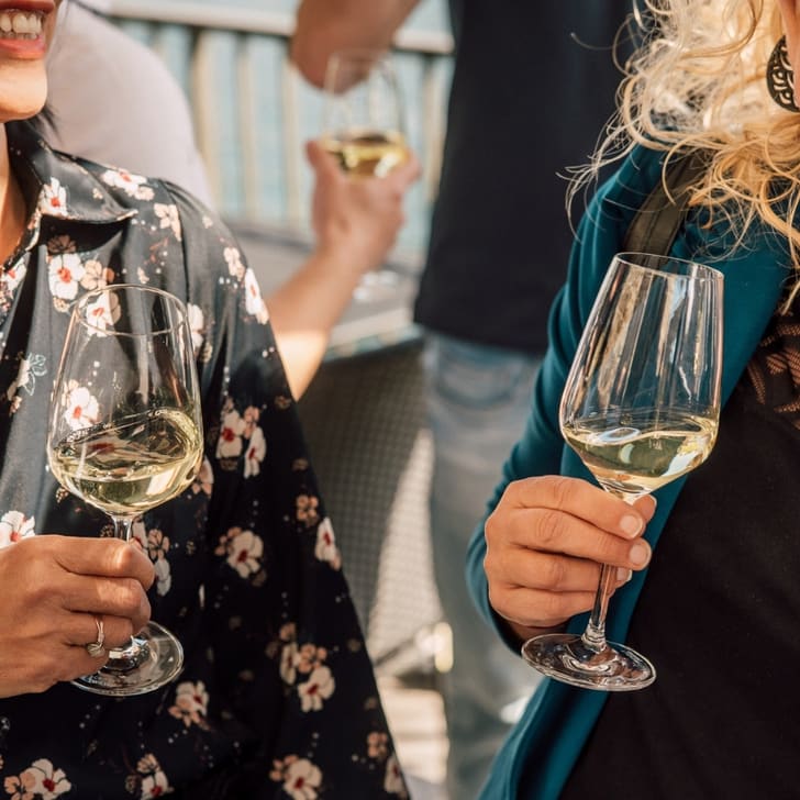 Zwei Frauen mit Weingläsern bei einem Treffen im Freien.