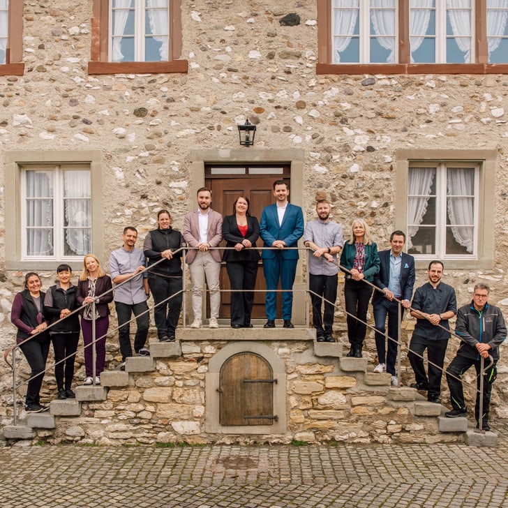 Gruppe von Menschen posiert auf Treppe vor steinernem Gebäude.