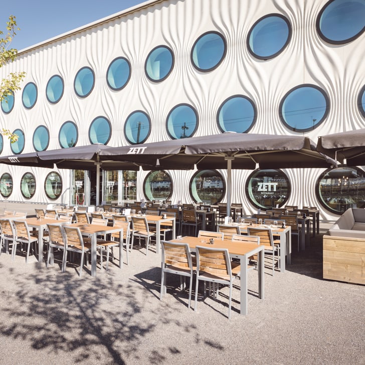 Aussenbereich eines Cafés mit runden Fenstern an der modernen Fassade.