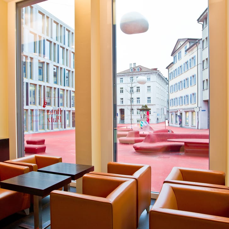 Innenansicht eines Cafés mit Blick auf moderne Gebäude und roten Platz.