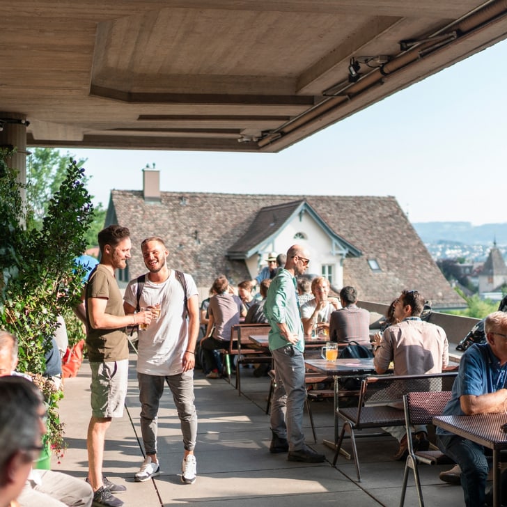 Menschen geniessen eine Terrasse mit Blick auf die Stadt im Sonnenschein.