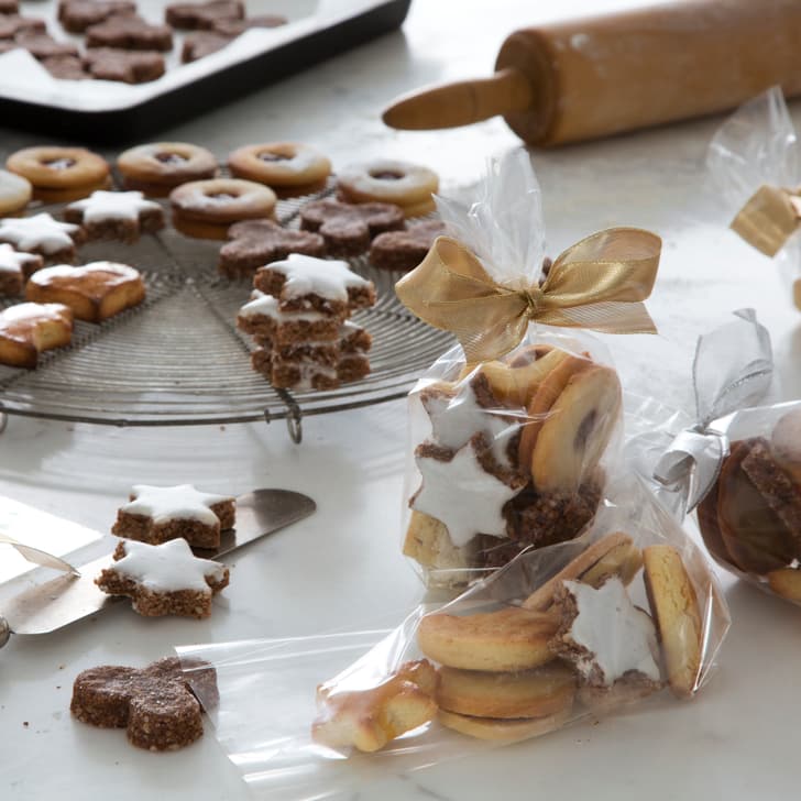 Weihnachtsplätzchen, Geschenkverpackungen und Backutensilien auf Tisch.