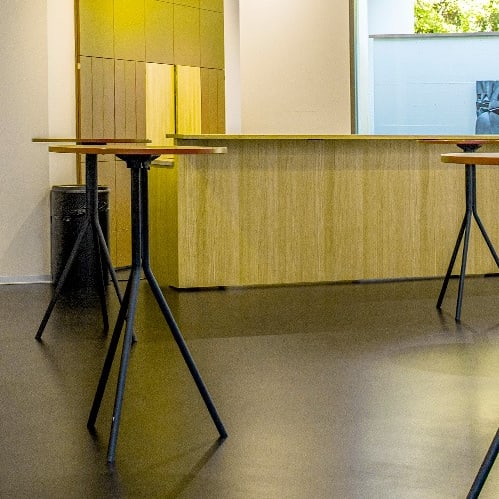 Moderner Empfangsbereich mit Stehtischen und Kunst an der Wand.