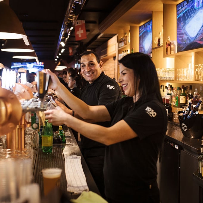 Barkeeper serviert Getränke in einer belebten Bar.