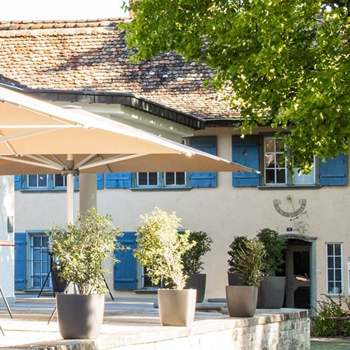 Aussenansicht eines Gebäudes mit Terrasse und Sonnenschirm.