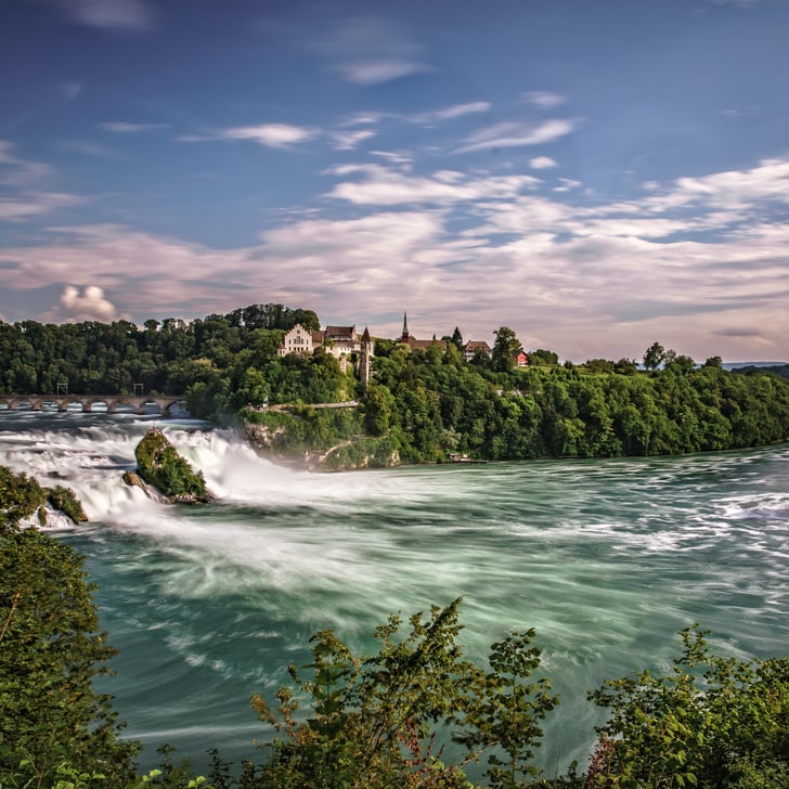 Landschaft mit grossem Wasserfall und bewaldeten Ufern.