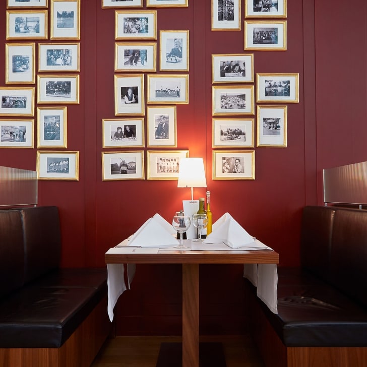 Restaurantkabine mit gerahmten Fotos an roter Wand.