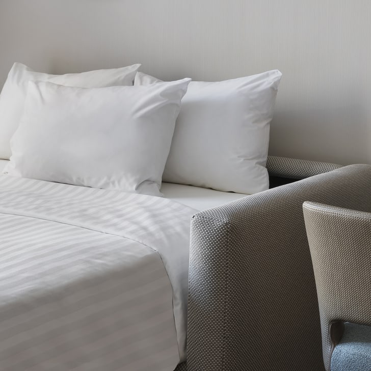 Zimmer mit Doppelbett und Tisch mit zwei Stühlen.