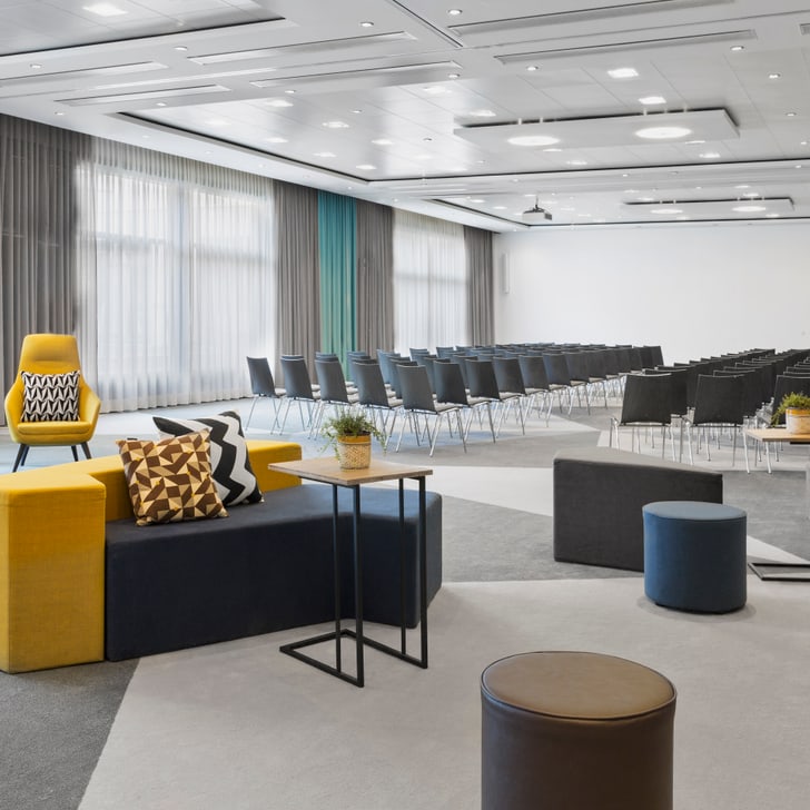 Konferenzraum mit Sitzreihen und Sofas.