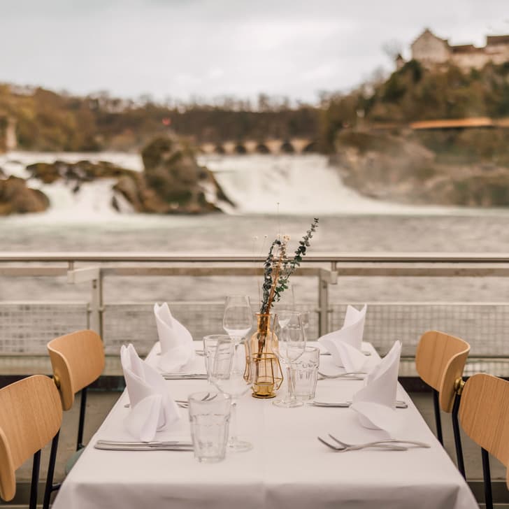 Gedeckter Tisch mit Aussicht auf Rheinfall und Schloss.
