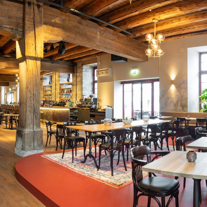 Gemütliches Restaurant mit Holzbalkendecke und Tischen.