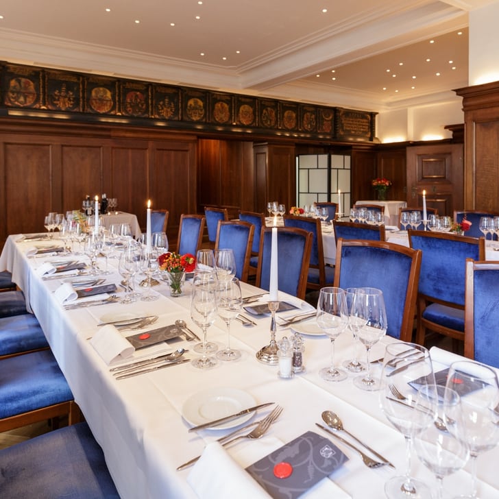 Elegantes Restaurant mit langen, eingedeckten Tischen und blauen Stühlen.