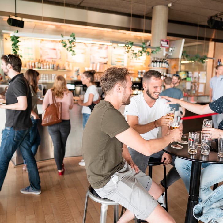 Menschen geniessen Getränke in einer belebten Bar.
