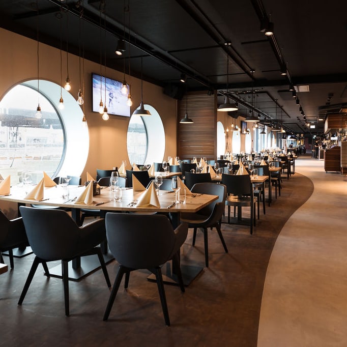 Restaurant mit gedeckten Tischen, Fenster mit Sportdekorationen.