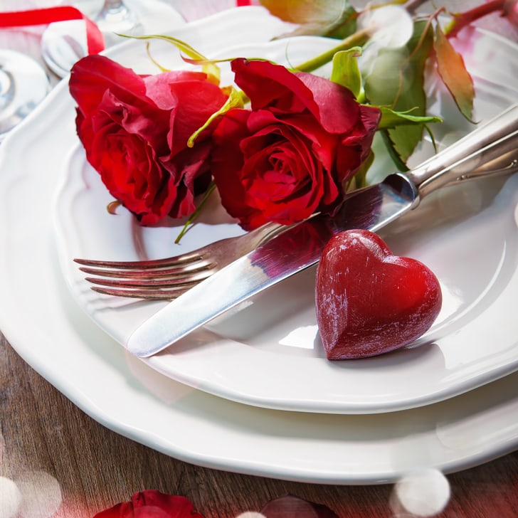Romantisches Abendessen-Setup mit Rosen und Kerzen.